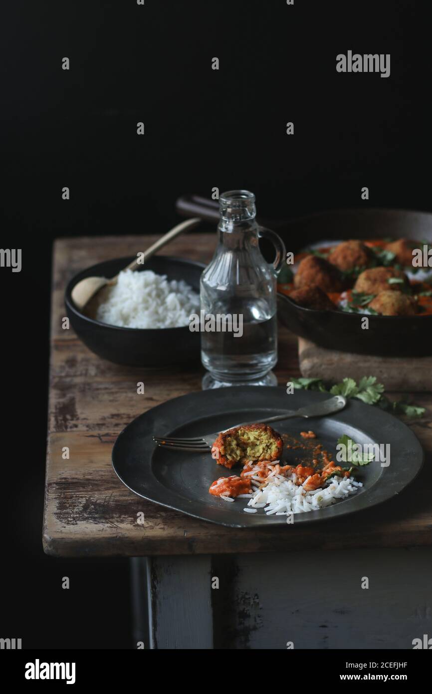 Bouteille d'eau en verre sur la table de bois près de bouillie boulettes de riz et de viande délicieuse avec persil et sauce Banque D'Images