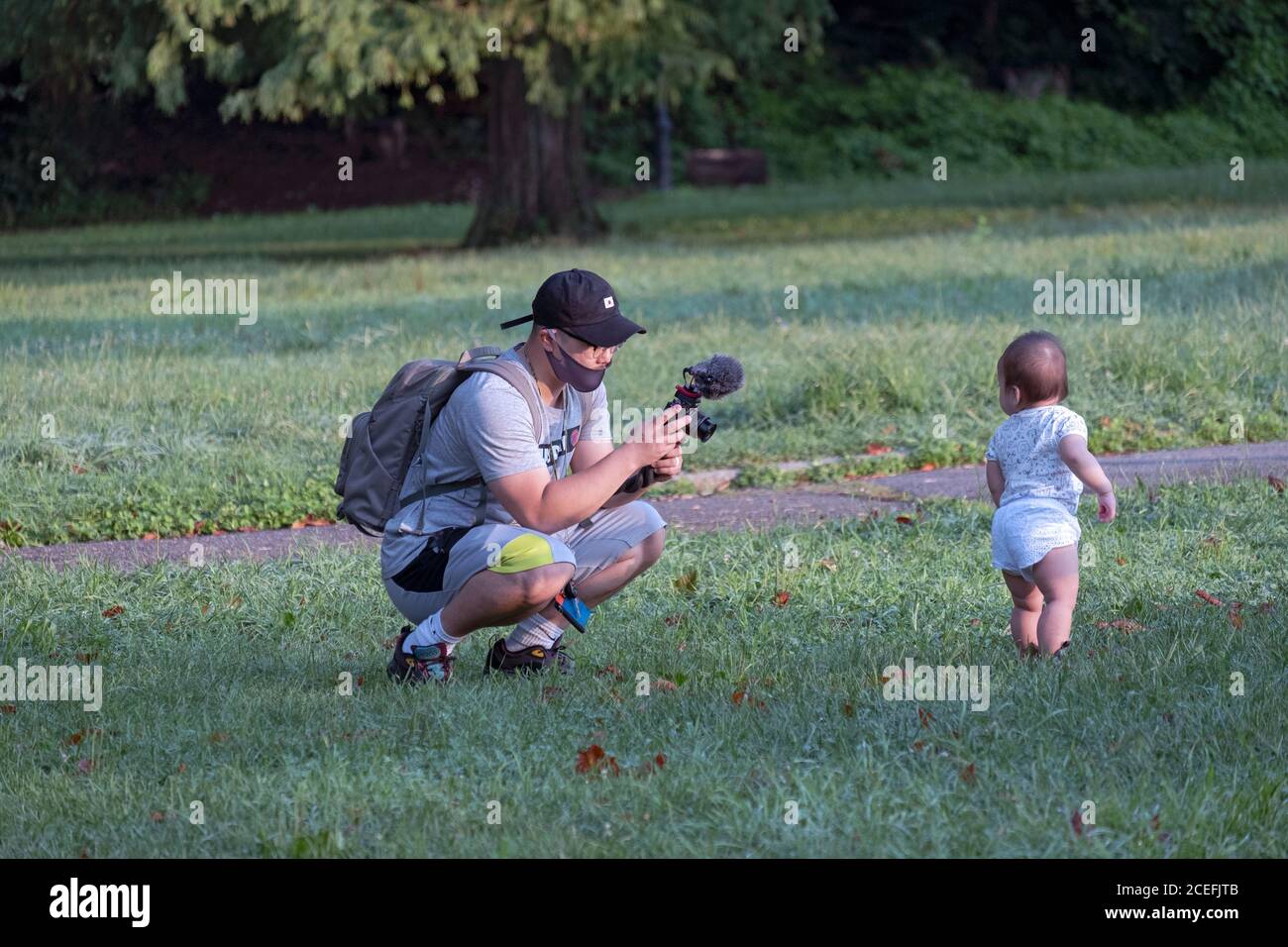 Un père américain coréen filme son enfant dans un parc à Queens, New York. Banque D'Images