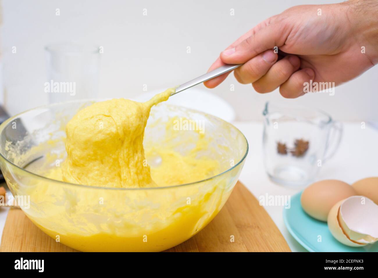 la pâte pour cupcakes faite de farine de riz, beurre, oeufs, sucre coule de la cuillère. gros plan de la texture de la pâte dans un plat transparent. Banque D'Images