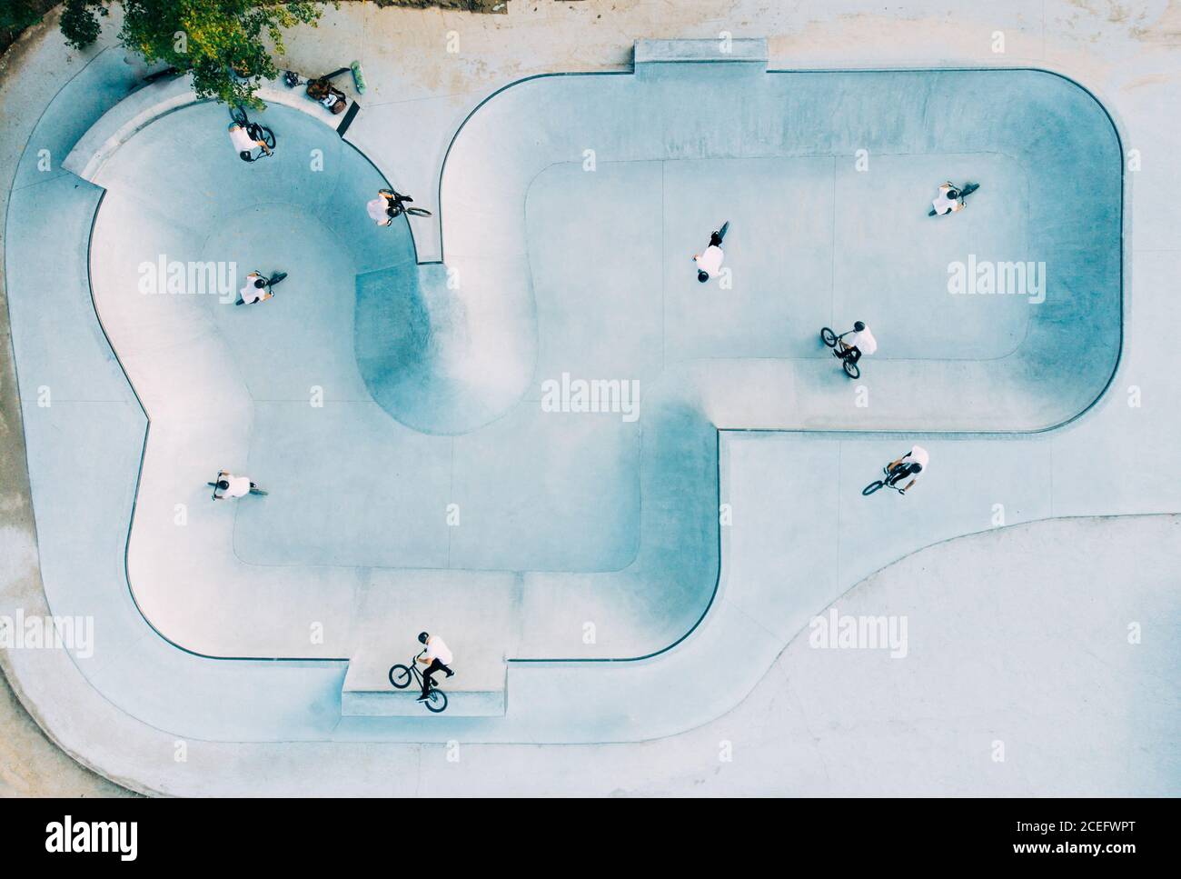 Vue d'en haut du grand parc de skate avec groupe de Hommes en T-shirts blancs faisant des tours sur BMX Banque D'Images Vue d'en haut du grand parc de skate avec groupe de Hommes en T-shirts blancs faisant des tours sur BMX Banque D'Images