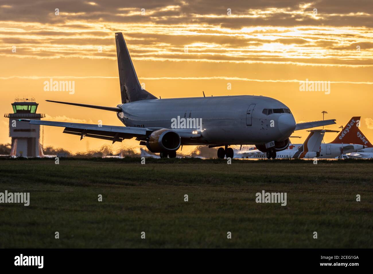 L'avion à réaction Titan Airways, qui travaille pour ASL Airlines pour transporter des colis Amazon, débarque à l'aube avec un ciel rouge de lever du soleil tandis que l'aéroport s'ouvre sur les pistes Banque D'Images