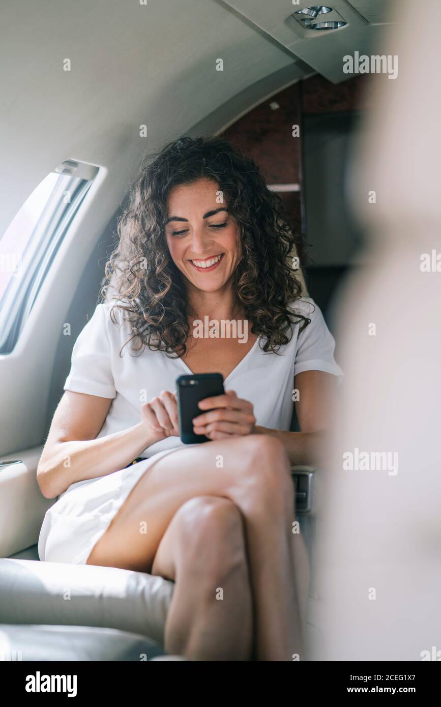 Jolie femme travaille avec un smartphone dans un avion. Banque D'Images