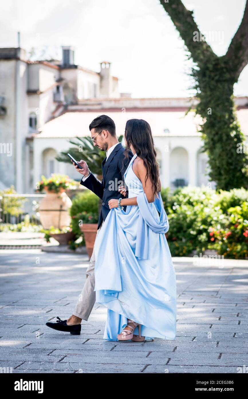 Un beau et élégant couple italien font leur chemin de l'autre côté de la place de la ville pour assister à un mariage. Ravello, Italie. Banque D'Images