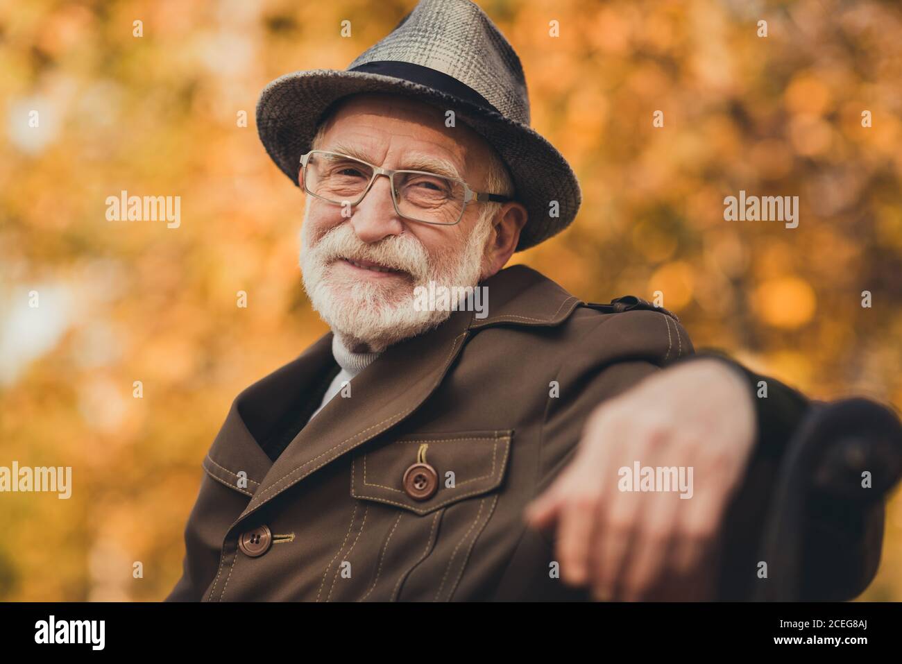 Gros plan photo de drôles heureux vieux retraité gris poil grand-père promenade dans le parc central profitez du soleil par temps chaud s'asseoir au banc pause pause vêtements élégants automne Banque D'Images
