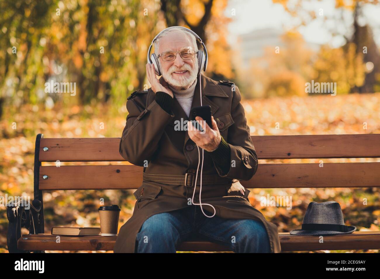 Photo de l'ancien retraité grand-père aux cheveux gris se sent jeune rue assis banc écouter cool jeune chanson grands rabats de la fermeture aux petits-enfants joyeux Banque D'Images