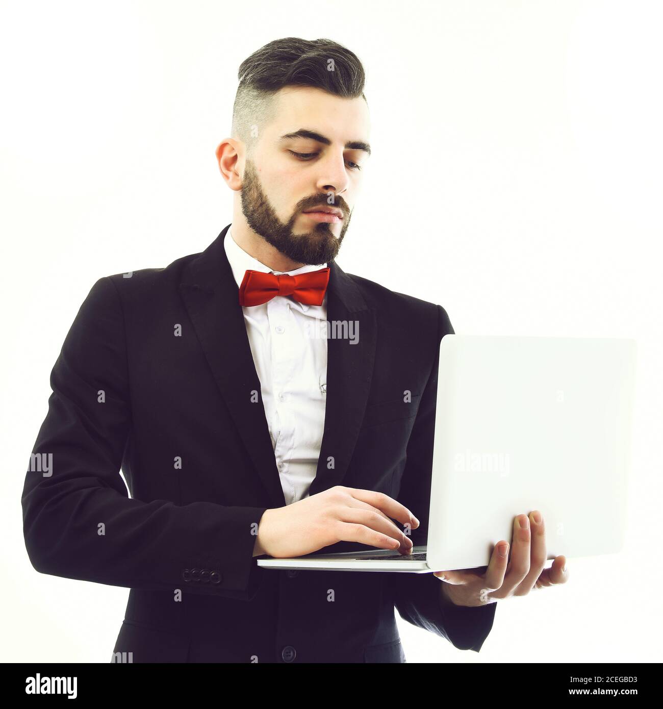 Homme d'affaires avec barbe et noeud papillon rouge tient l'ordinateur  portable blanc et le regarde avec un visage sérieux, isolé sur fond blanc.  Concept d'importance et d'affaires Photo Stock - Alamy