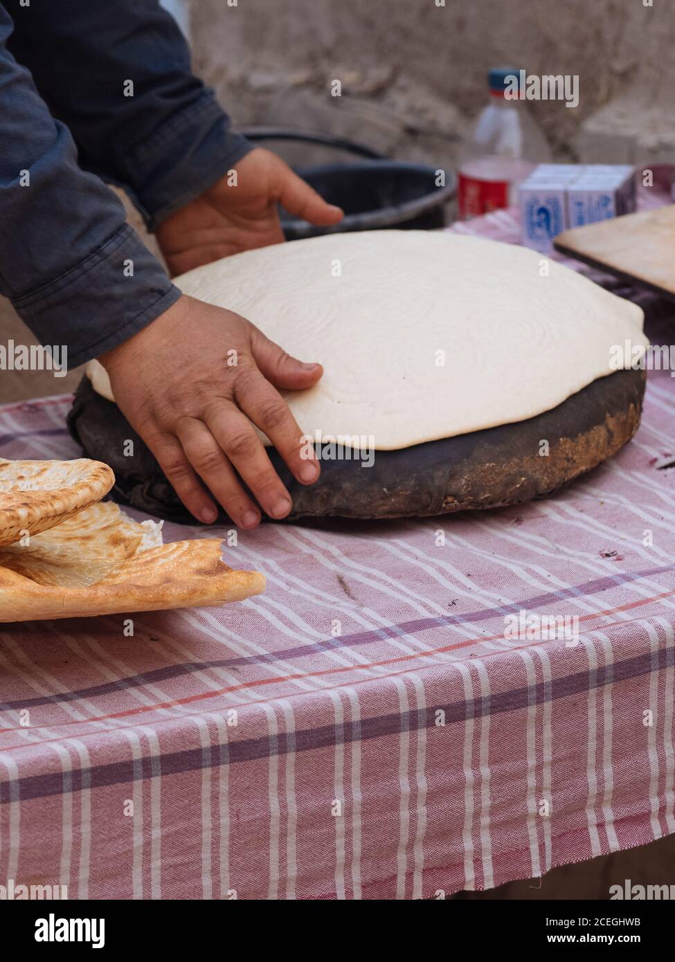 Vue de côté de la récolte de femme roulant de la feuille de pâte sur bois dehors tout en faisant un plat traditionnel, Ouzbékistan Banque D'Images