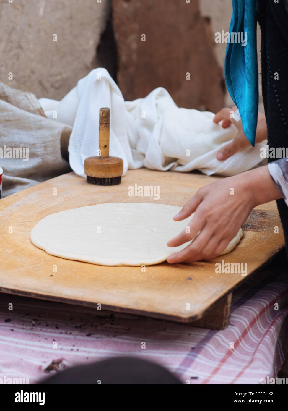 Vue de côté de la récolte de femme roulant de la feuille de pâte sur bois dehors tout en faisant un plat traditionnel, Ouzbékistan Banque D'Images