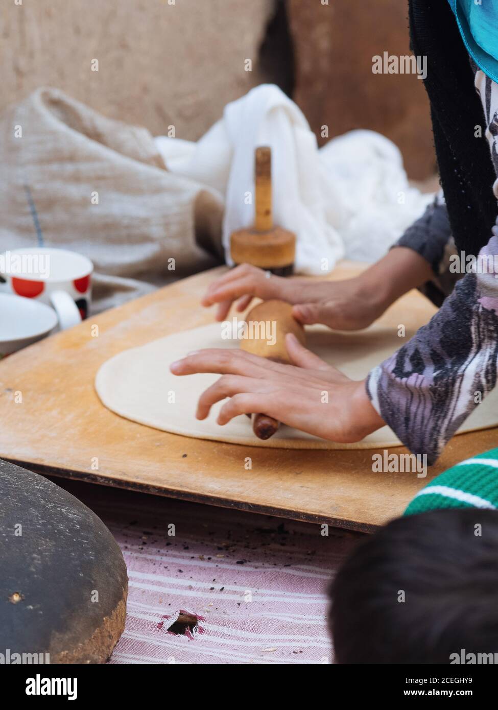 Vue de côté de la récolte de femme roulant de la feuille de pâte sur bois dehors tout en faisant un plat traditionnel, Ouzbékistan Banque D'Images
