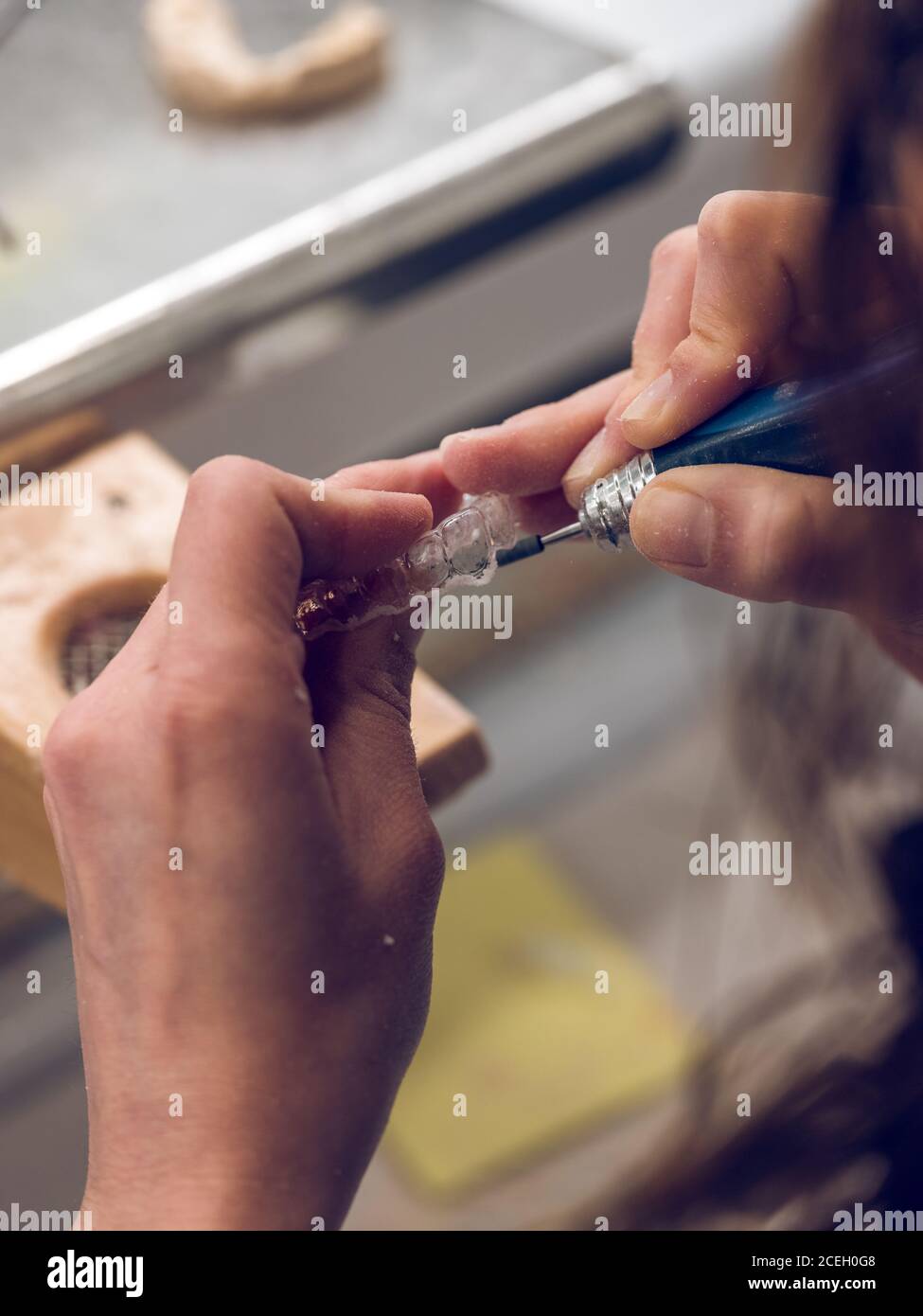 Rognez les mains d'un technicien féminin à l'aide d'un outil pour fabriquer un plateau dentaire en laboratoire. Banque D'Images