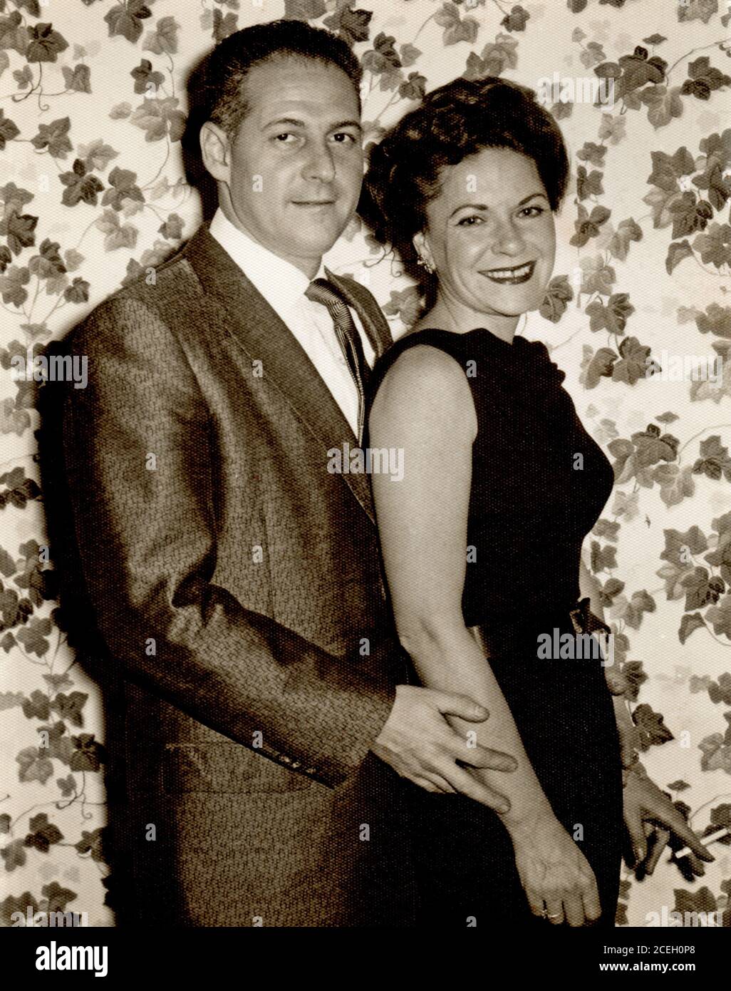 Heureux a posé un couple vers les années 1960 vêtu de vêtements de soirée à la mode, femme tenant la cigarette. Banque D'Images