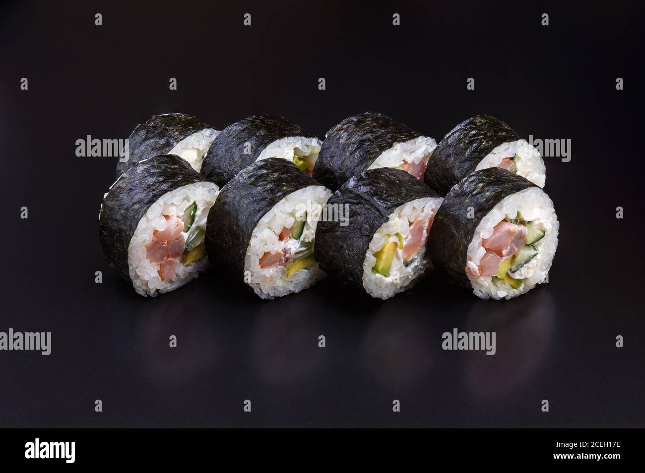 Délicieux sushi Maki traditionnel aux crevettes fraîches sur fond noir avec reflets. Roulé à sushis avec riz, fromage à la crème, avocat, saumon. SHR Banque D'Images
