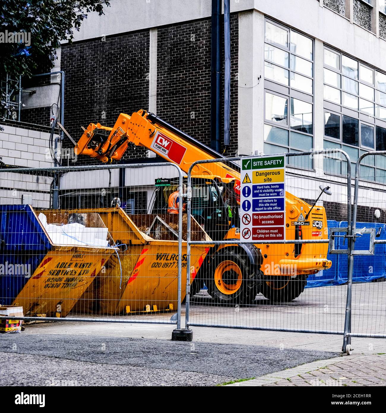 Équipement de construction de chariot élévateur et bennes à ordures avec Santé et Consignes de sécurité derrière UNE clôture de sécurité Banque D'Images