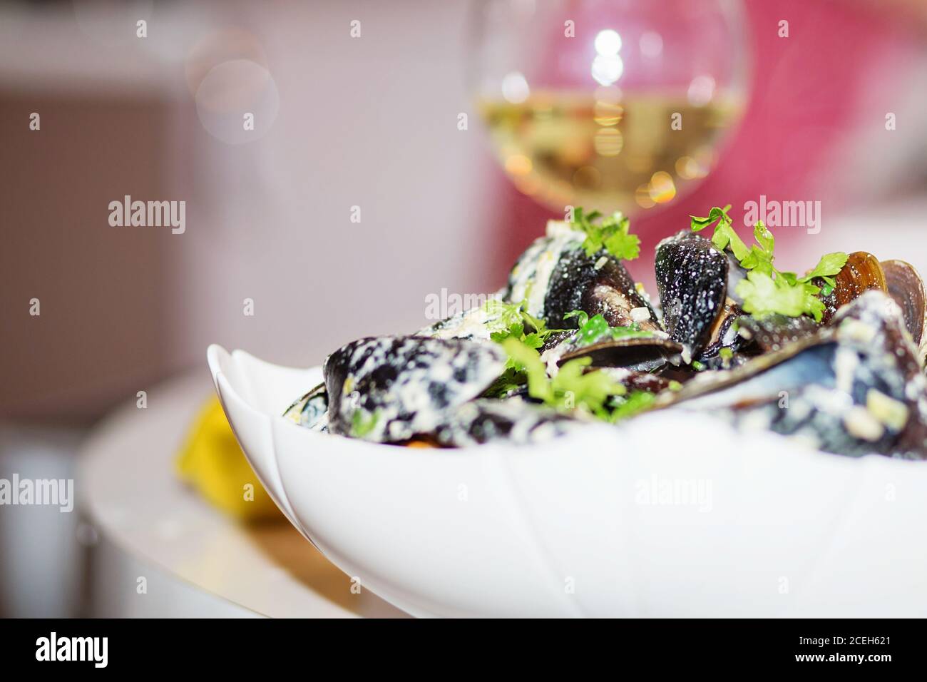 Moules cuites à la vapeur dans une sauce au fromage. Moules en coquilles dans le bol avec vin blanc sur la table. Banque D'Images