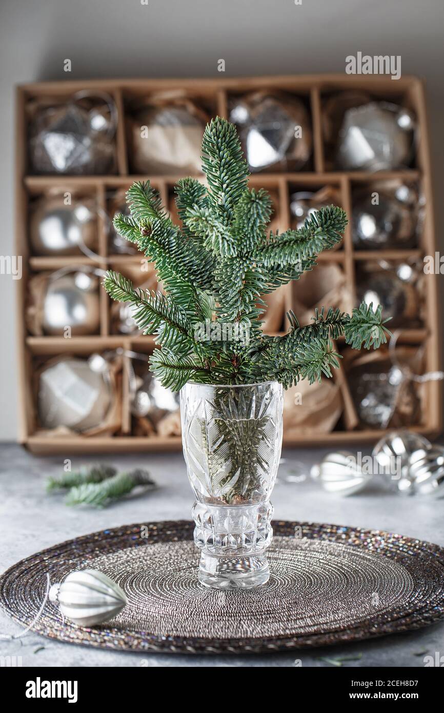 Un bouquet de branches de sapin dans un vase en cristal face d'une grande  boîte en carton avec des boules de Noël en argent. décorations de noël  maison. Compo de Noël Photo