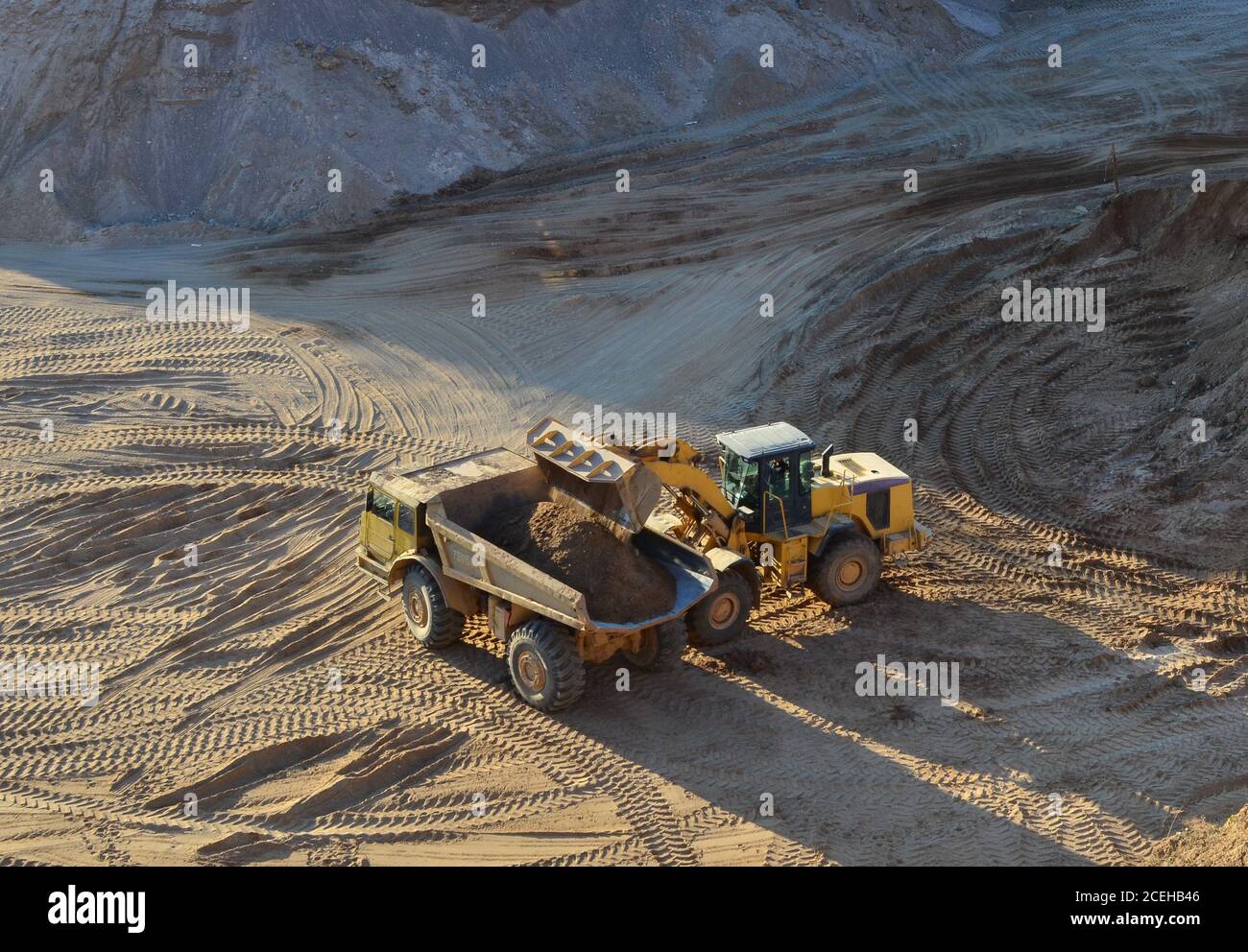 La chargeuse sur pneus charge le sable dans un camion-benne pour applications minières lourdes à la carrière minière en plein dépôt. Machines lourdes dans la fosse ouverte, excavateurs, tracteurs et camions. Di Banque D'Images