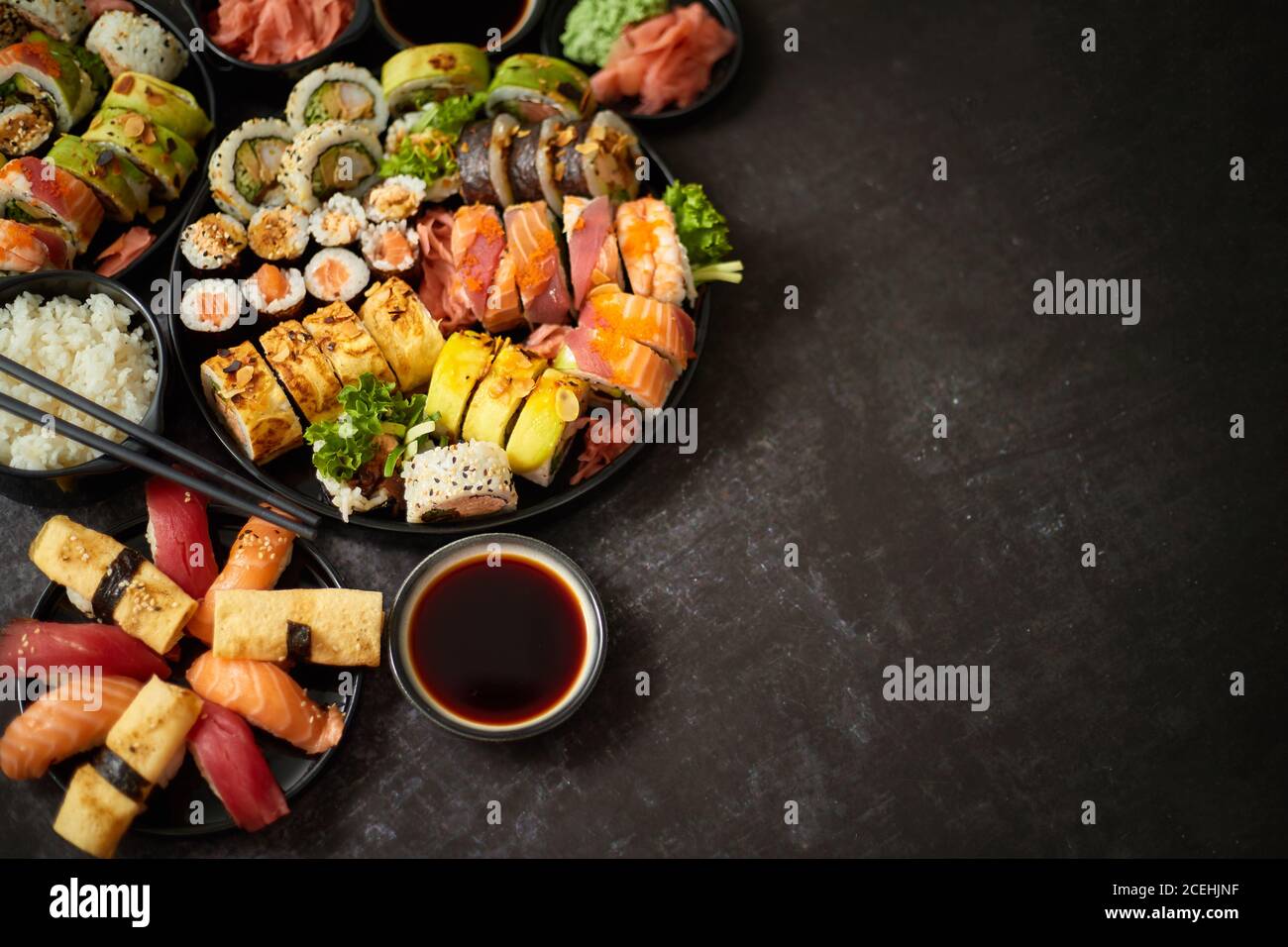 Assortiment de sushis servi sur fond sombre. Vue de dessus des fruits de mer, divers petits pains maki Banque D'Images