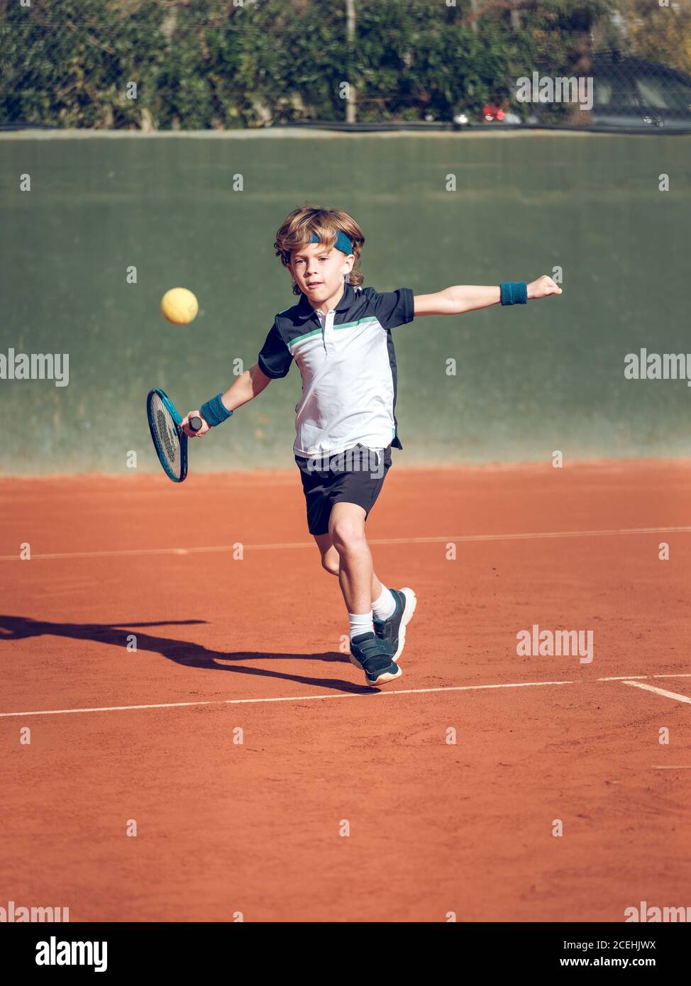 Petit enfant dans des vêtements de sport avec raquette de tennis essayant  de frapper ballon suspendu dans l'air sur le terrain par beau temps Photo  Stock - Alamy