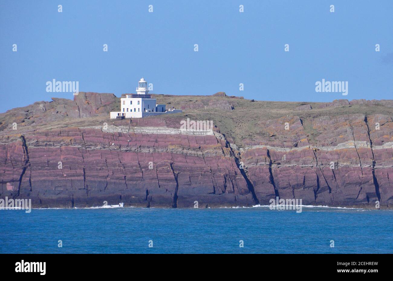 Les couches multicolores de vieux grès sous le phare de St Annes Head, Milford Haven, Pembrokeshire, South Wales, Royaume-Uni Banque D'Images