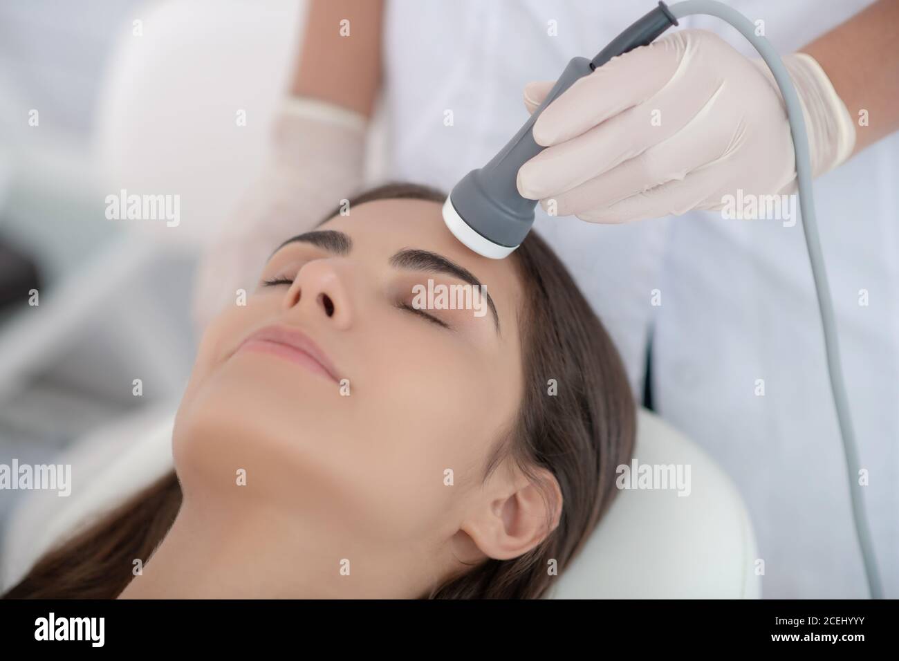 Un cosmétologue qui effectue un lissage laser du visage pour le client Banque D'Images
