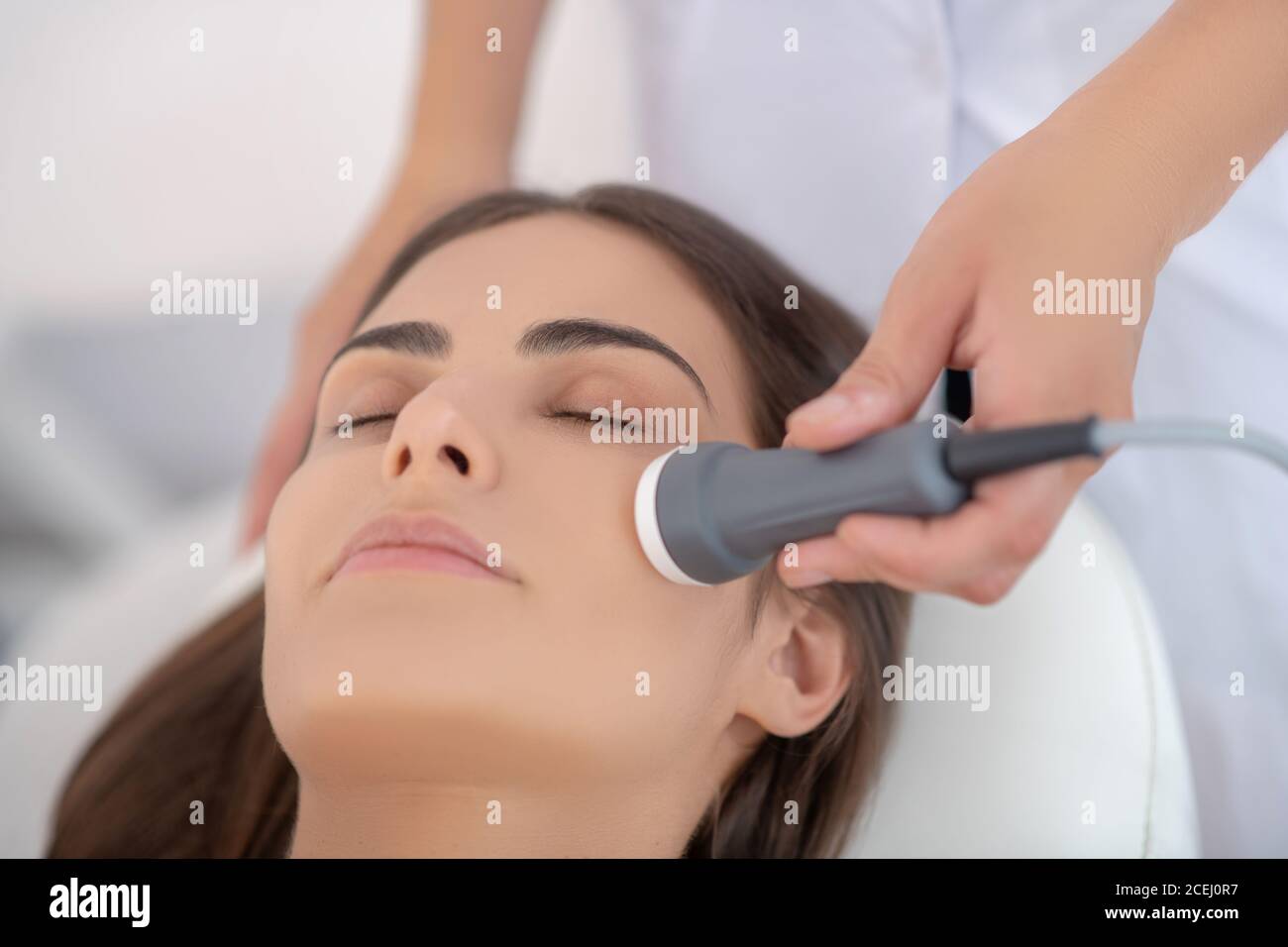Un cosmétologue qui effectue un lissage laser du visage pour la cliente Banque D'Images