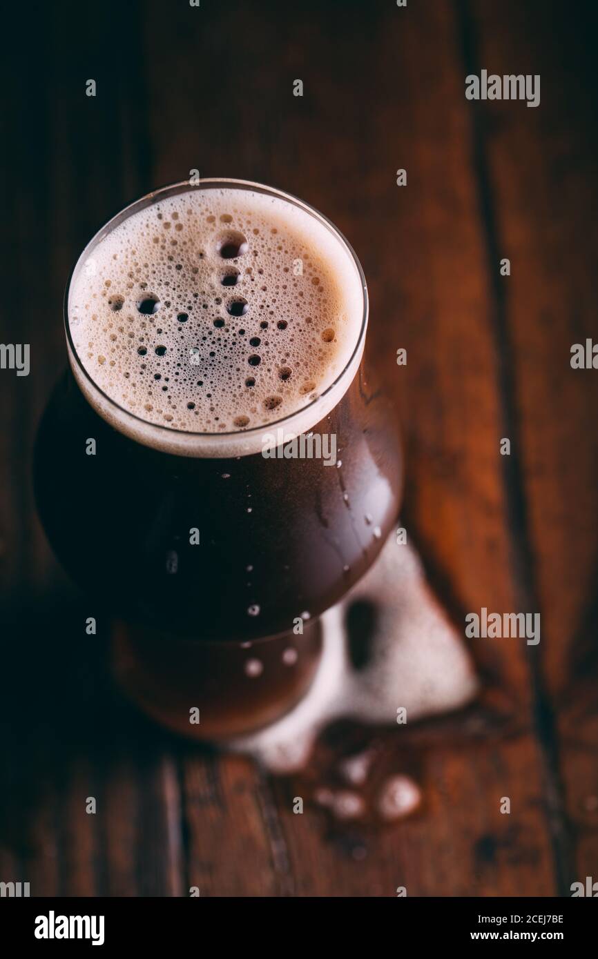 Bière piquant dans le verre sur fond sombre Banque D'Images
