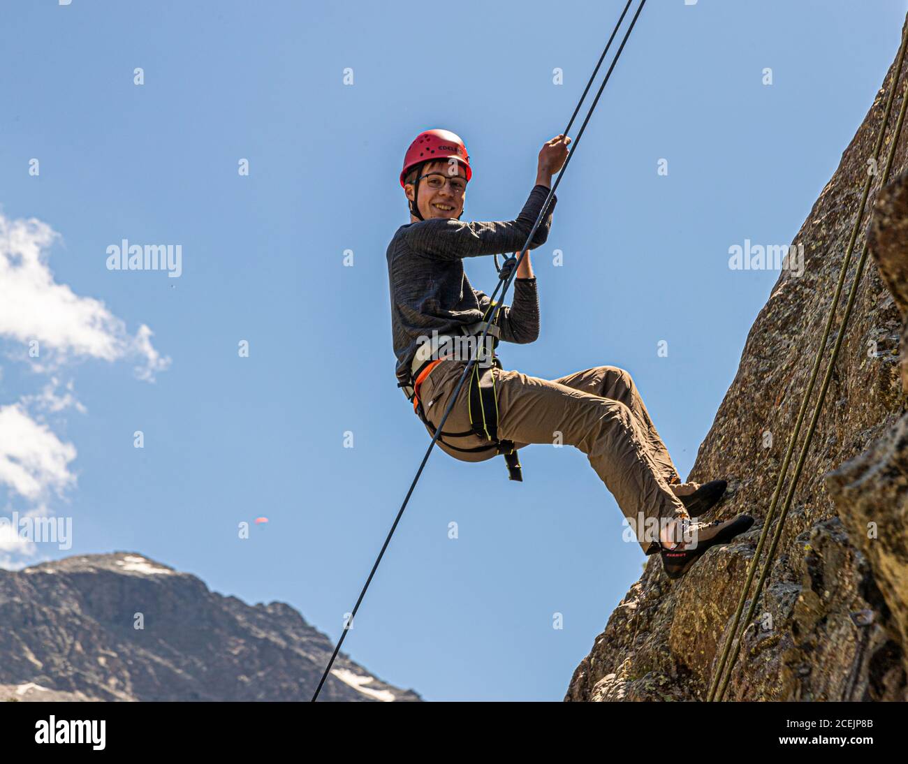 Un jeune homme a enfoncé un rocher en face de Piz Palü. La descente en rappel devant le massif de Piz Palü est la récompense à la fin du cours d'escalade d'introduction. Escalade à Pontresina, Suisse Banque D'Images