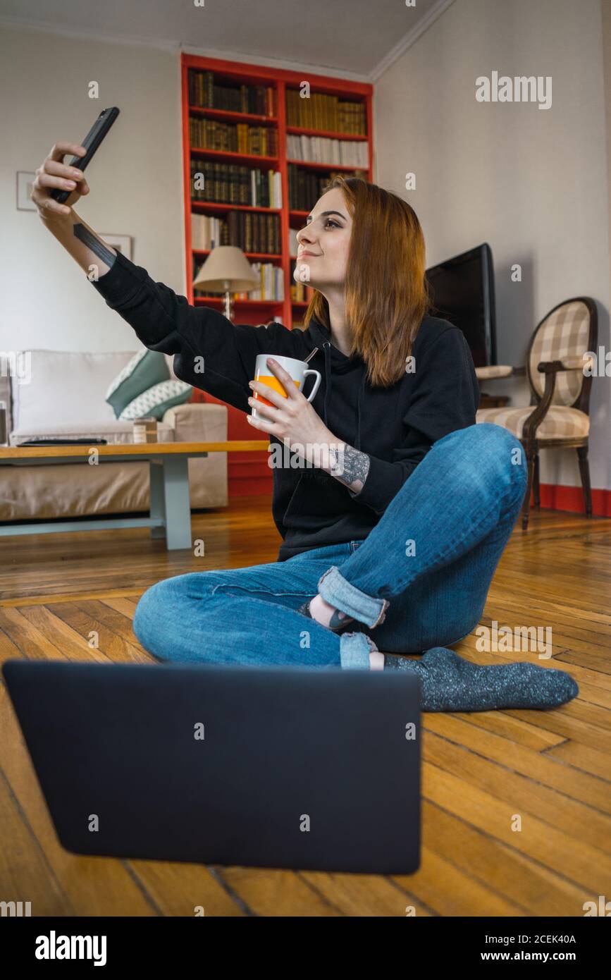Femme prenant le selfie assis sur le sol Banque D'Images