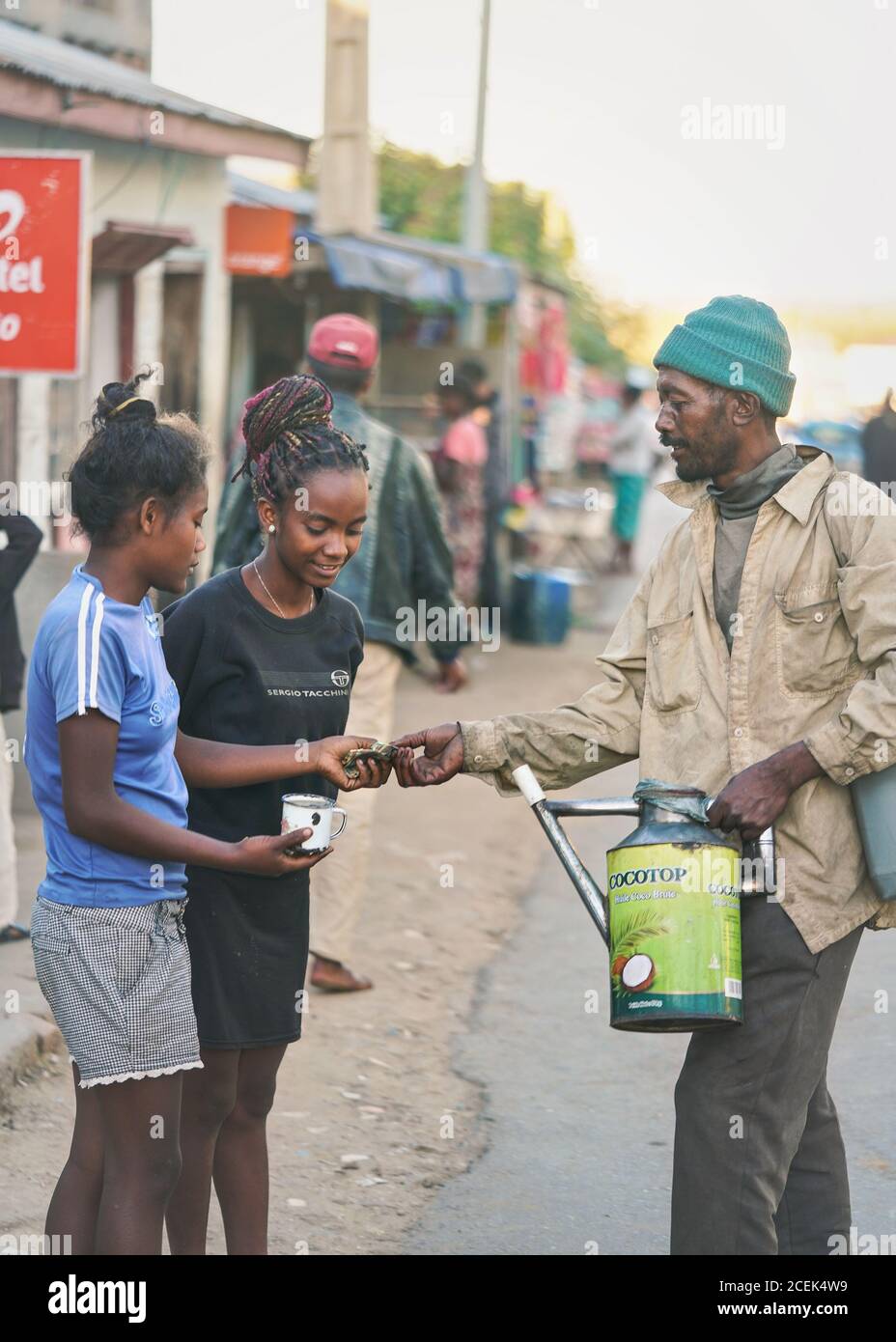 Ranohira, Madagascar - 29 avril 2019: Homme malgache inconnu vendant des boissons aux fruits à deux jeunes filles dans la rue, en versant directement de la saupoudrer t Banque D'Images