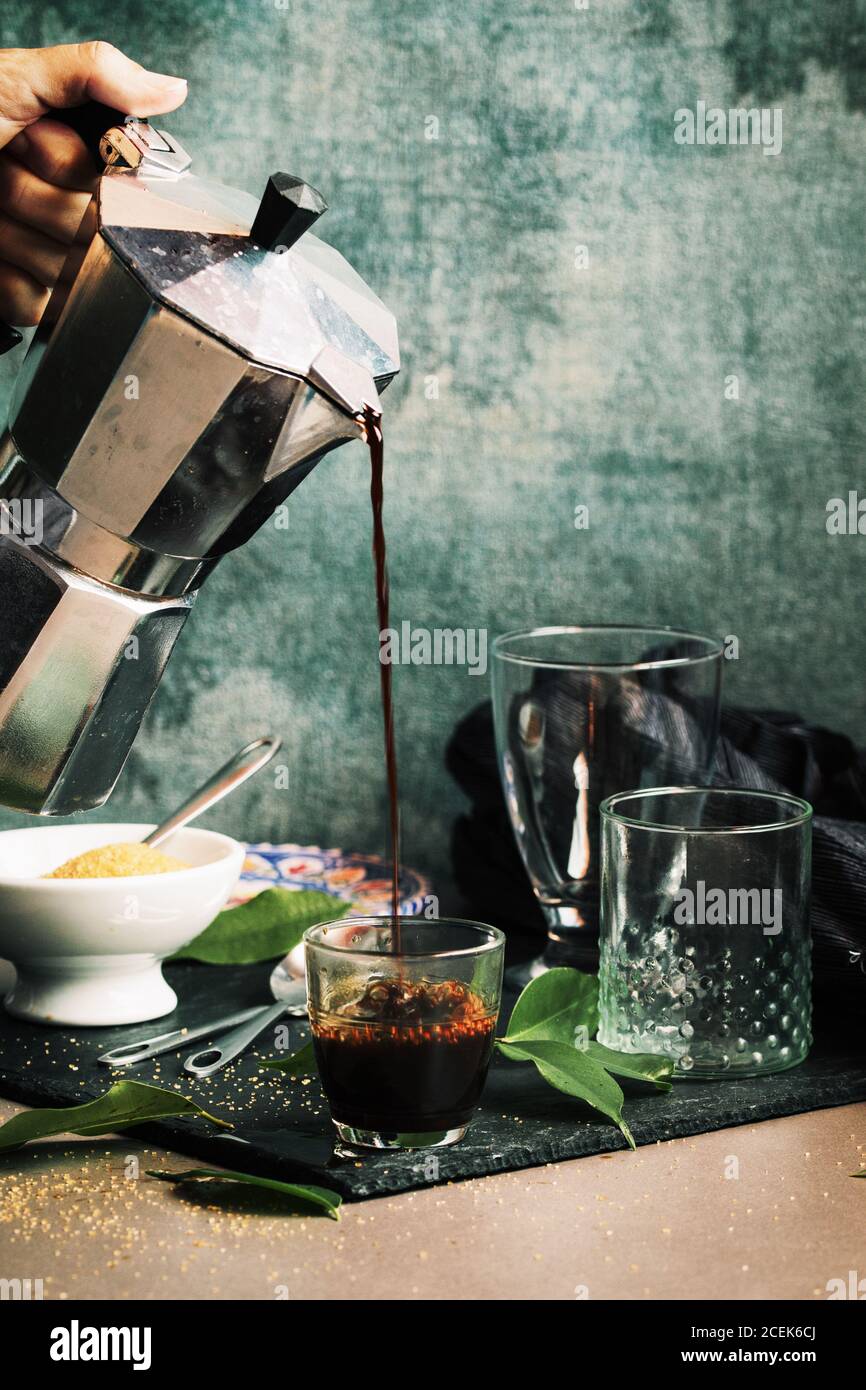 Main femme servant le café dans le verre de cristal Banque D'Images