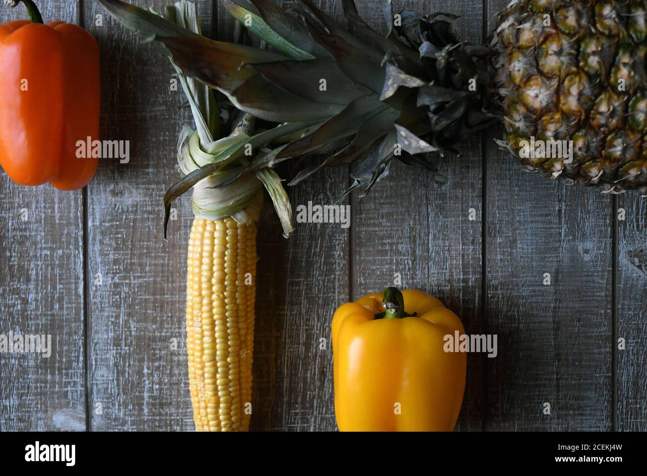 PARTY MIX: Un mélange de fruits et de légumes qui comprennent des poivrons, de l'ananas, et du maïs sur l'épi sont disposés ensemble sur une planche à découper en bois. Banque D'Images