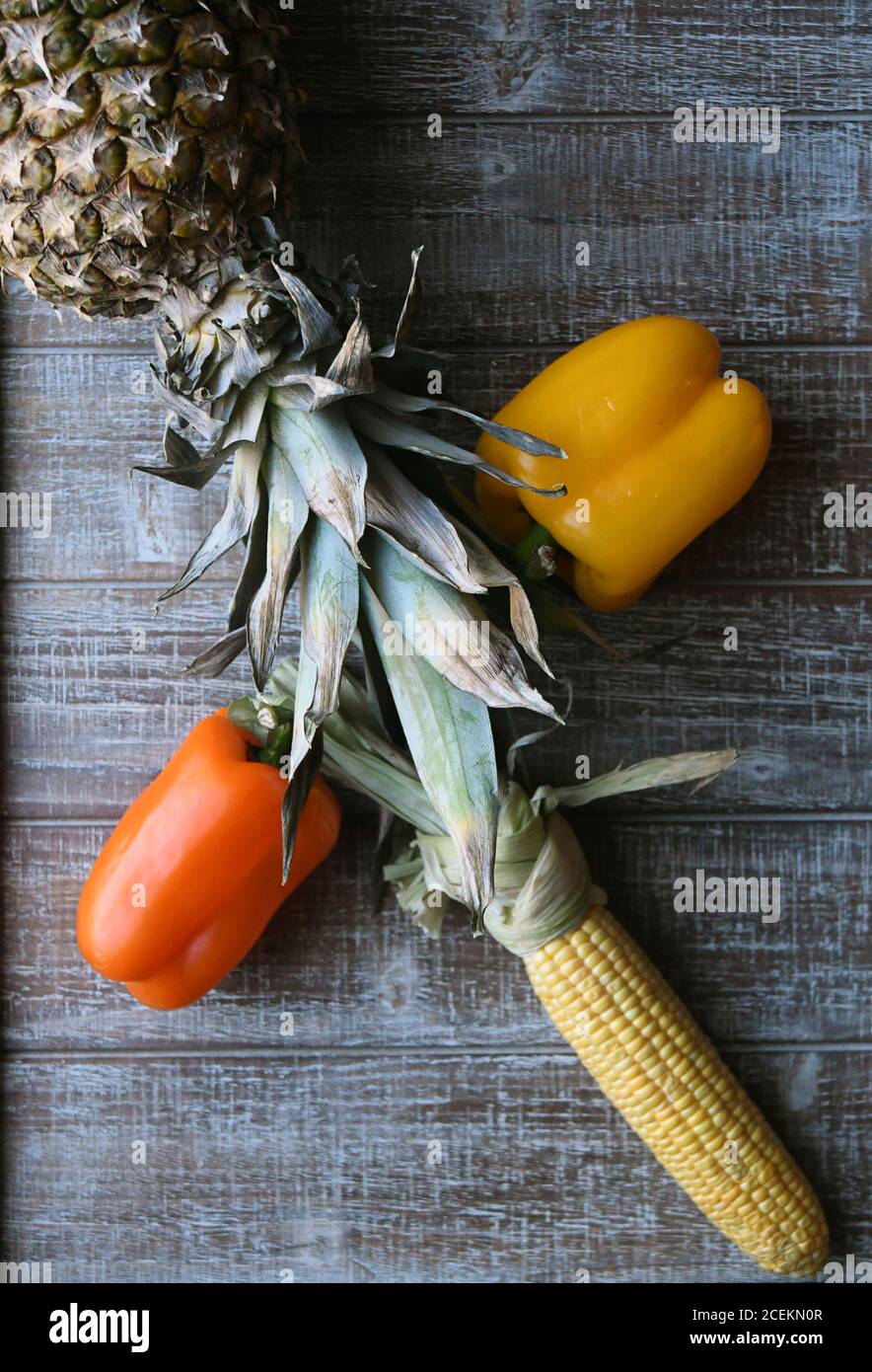 PARTY MIX: Un mélange de fruits et de légumes qui comprennent des poivrons, de l'ananas, et du maïs sur l'épi sont disposés ensemble sur une planche à découper en bois. Banque D'Images