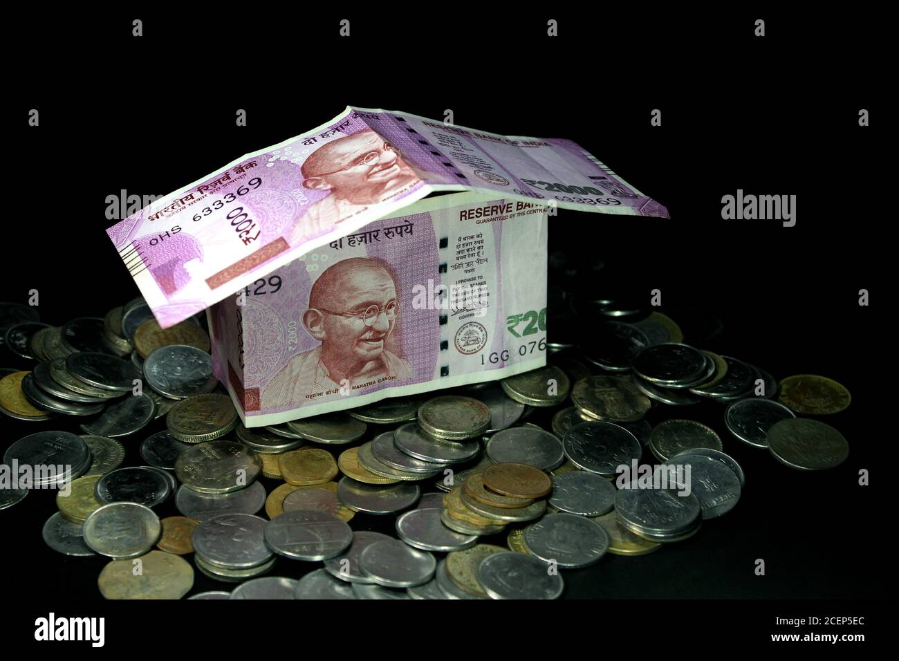 Concept de billets de banque de roupie indienne pliés en forme d'une maison simple sur fond noir. Nouvelle monnaie indienne. note de 2000 roupies avec pièces. Banque D'Images
