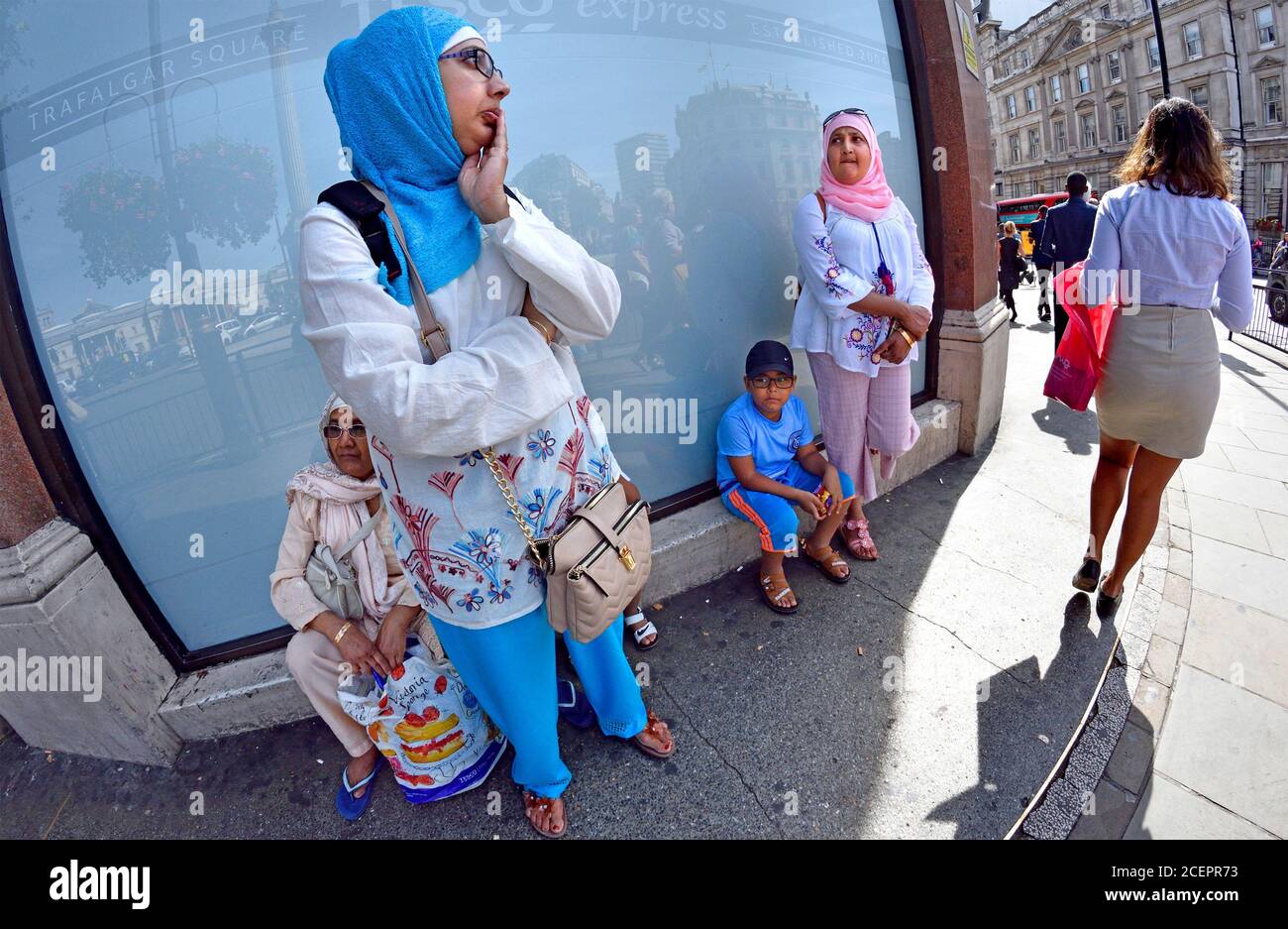 Londres, Angleterre, Royaume-Uni. Famille musulmane à l'extérieur de la boutique Tesco à Trafalgar Square Banque D'Images