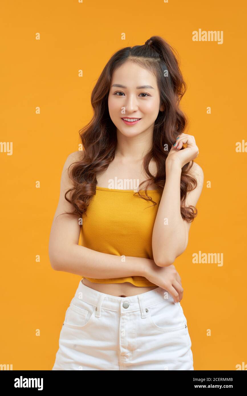 Joyeuse jeune femme asiatique en jaune crop top posant isolé sur fond jaune. Banque D'Images