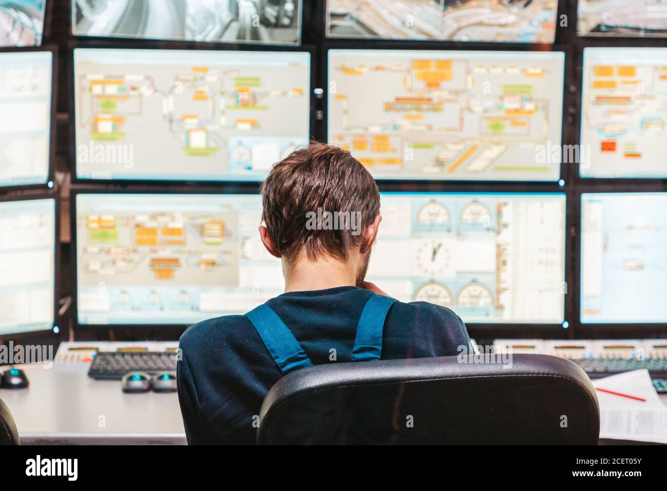 Le concept de la vidéosurveillance. Vue arrière de l'opérateur du système de sécurité regardant les vidéos de vidéosurveillance au bureau. Banque D'Images