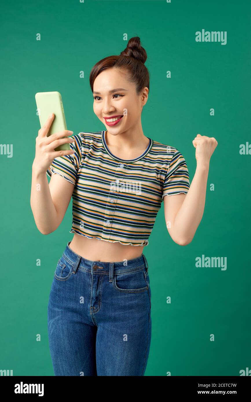 Belle femme sociable avec l'aspect asiatique prenant le selfie ou parlant lors d'un appel vidéo à l'aide d'un téléphone portable isolé sur fond vert Banque D'Images