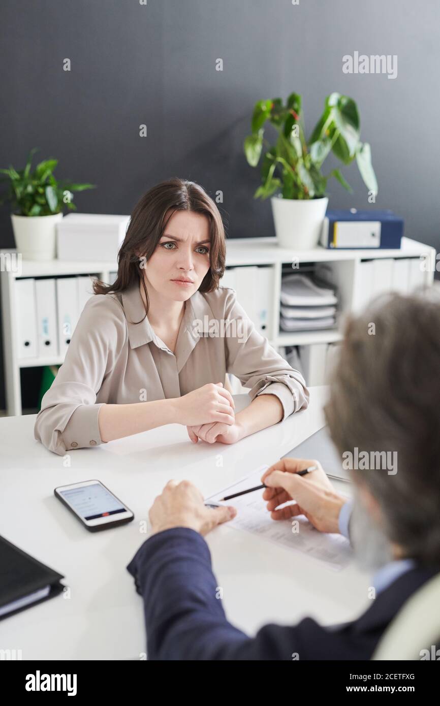 Une jeune femme se sent confondue avec des questions absurdes que le responsable des ressources humaines lui pose lors d'un entretien d'embauche, un cliché vertical grand angle Banque D'Images