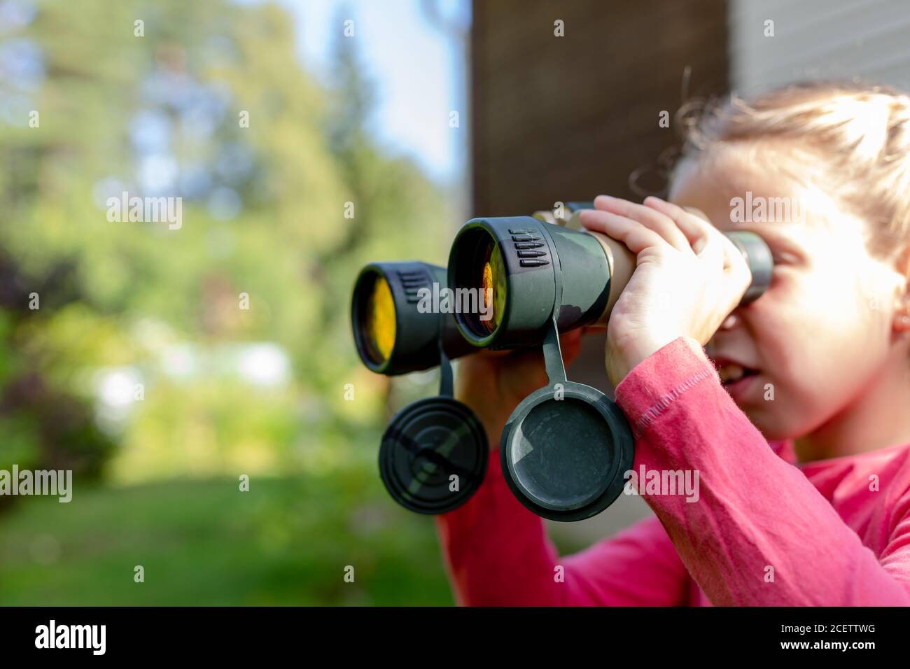Petite Fille Blonde Regardant A Travers Des Jumelles Sur Fond De Nature Bebe Cacha Dans La Verdure Et Est Assis Dans Une Embuscade Concept Aventure Pour Enfants L Enfant Photo Stock Alamy