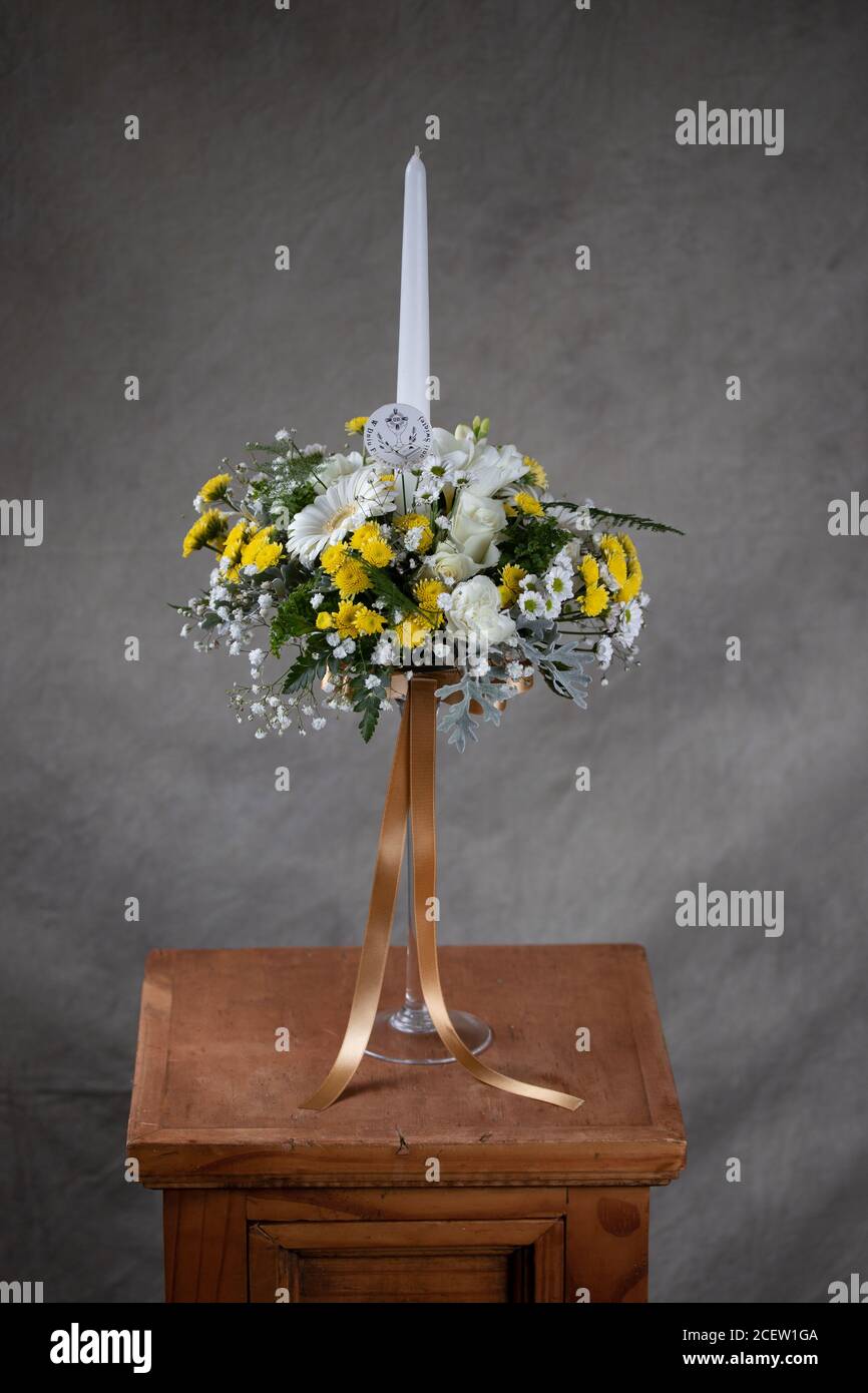 Bouquets de fleurs de la première sainte communion. Bougie blanche décorée  de fleurs blanches et jaunes. Fond gris Photo Stock - Alamy