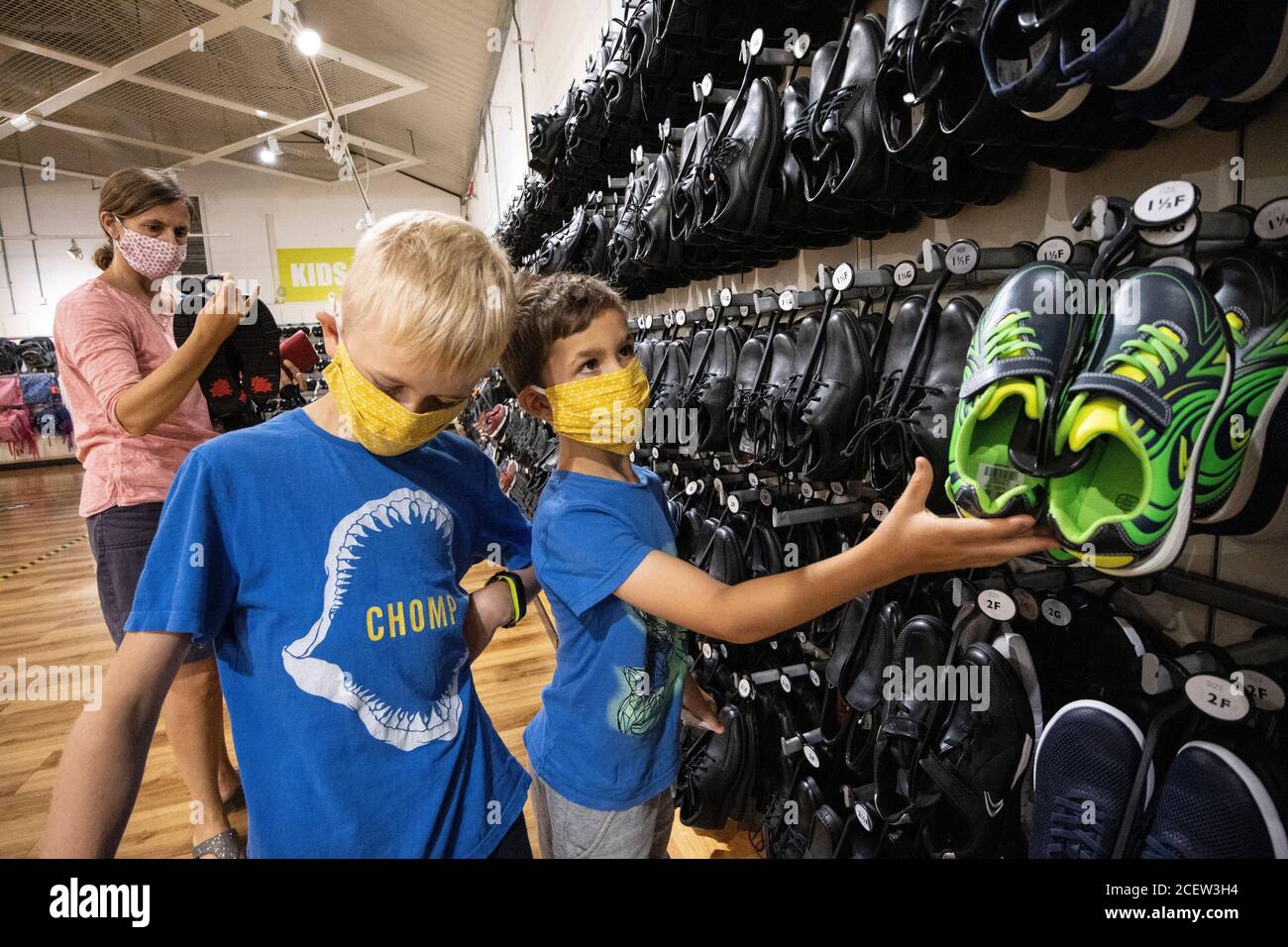 Retour à l'école, une mère et des fils achètent leurs chaussures de retour à l'école dans un magasin de chaussures Clarks à Street, Somerset, Angleterre, Royaume-Uni Banque D'Images