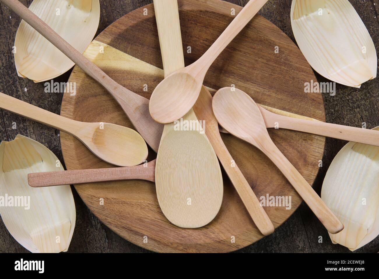 Vue de dessus sur les ustensiles de cuisine en matériaux recyclables : cuillères sur une assiette en bois et bols en papier de bambou Banque D'Images