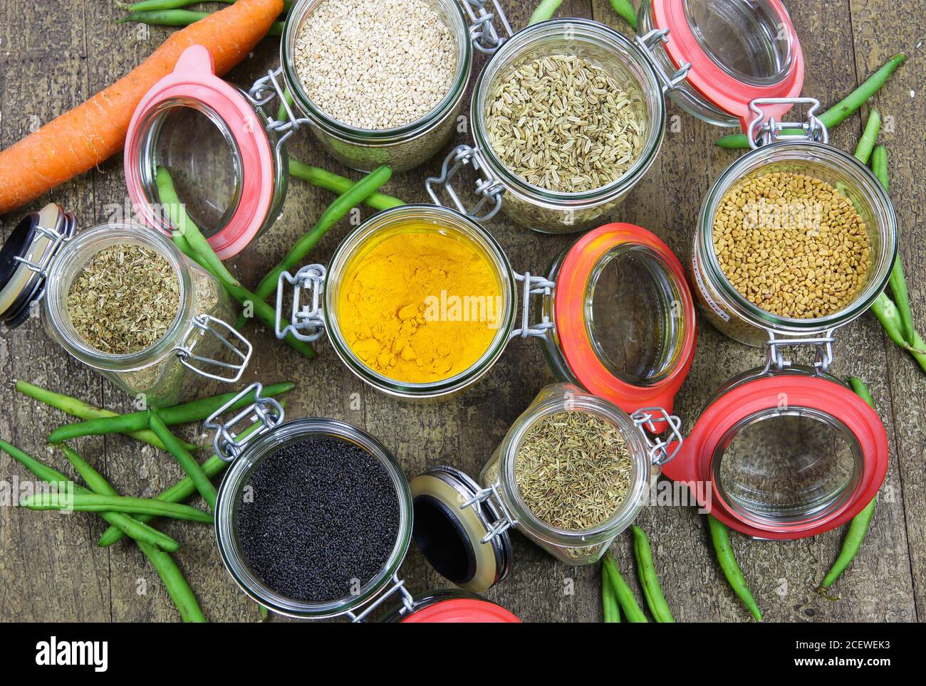 Vue de dessus sur les bocaux de conservation isolés avec variété de coloré condiments sur table en bois - concept d'emballage sans plastique Banque D'Images