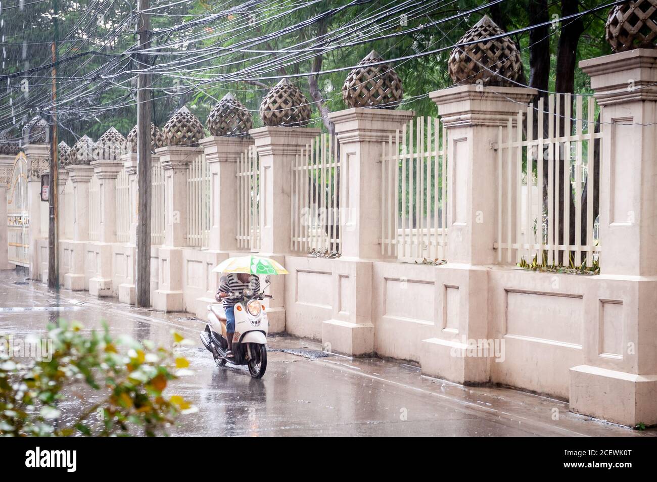 Un mobylette fait lentement son chemin le long de soi 10 au large de Sukhumvit Rd. Bangkok pendant une forte pluie en chute. Banque D'Images