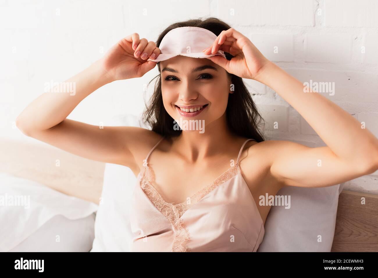 jeune femme en soie nouée touchant le masque rose pour les yeux Banque D'Images