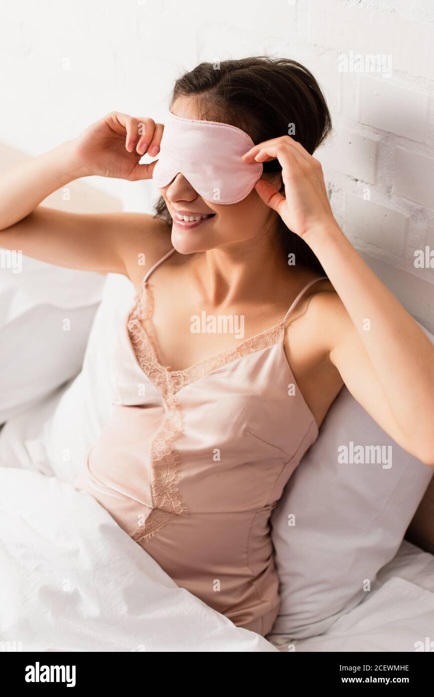 jeune femme enceinte en nightie touchant le masque rose pour les yeux Banque D'Images