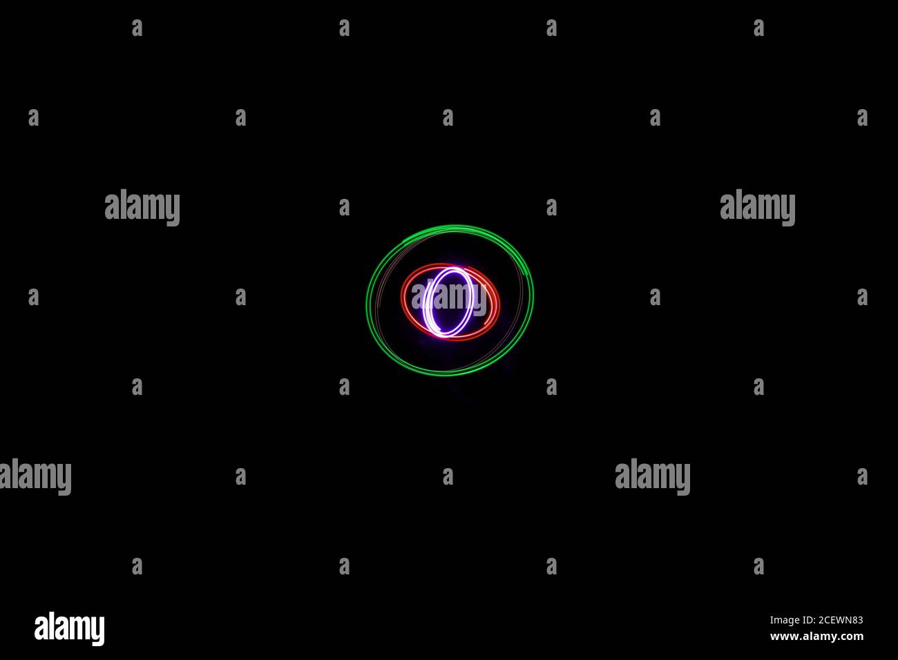 vert rose bleu elliptique lumière peinture photographie, exposition longue, ondulations et ondulations sur un fond noir Banque D'Images