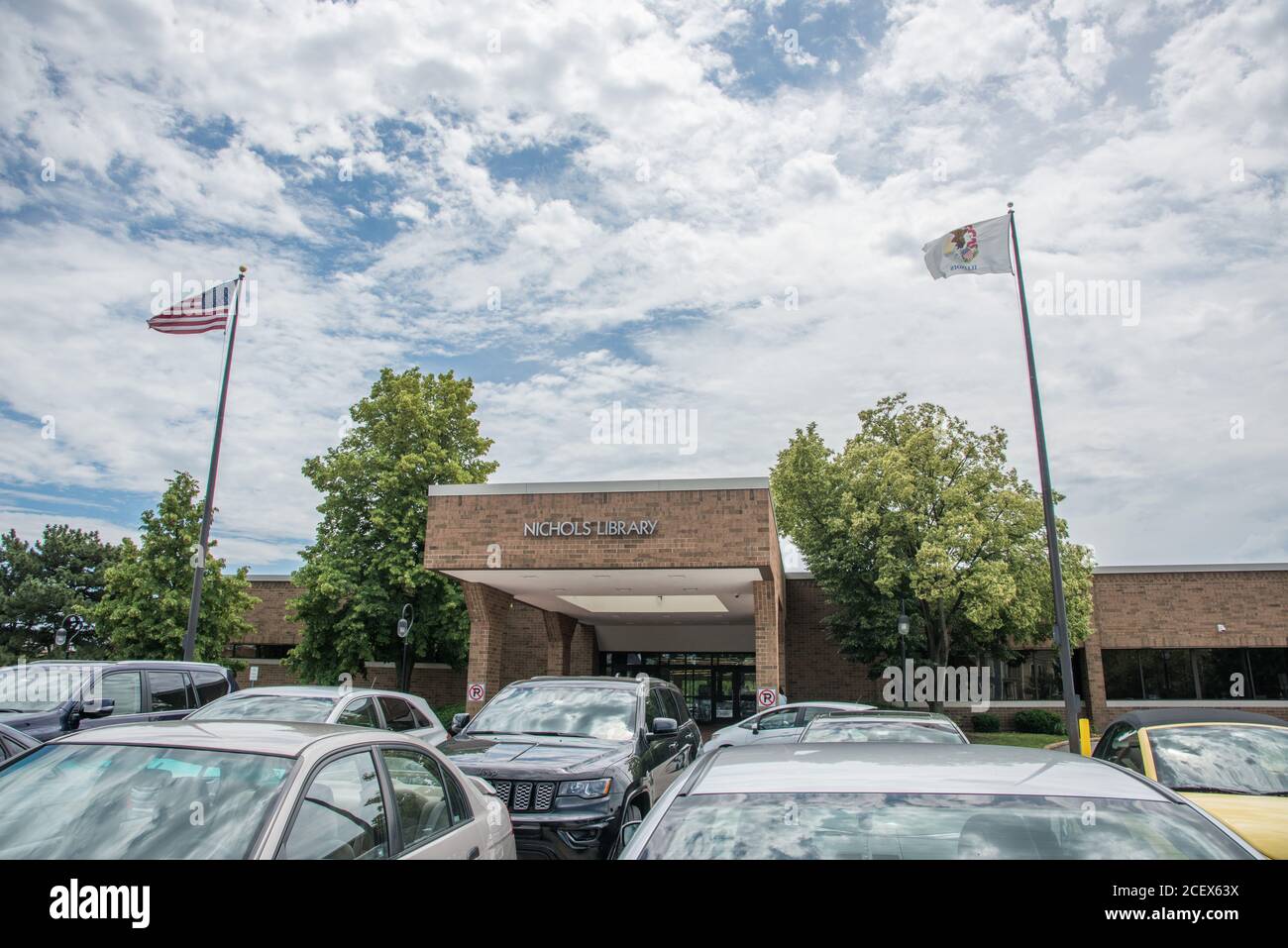 Naperville, Illinois, États-Unis-avril 24,2014 : édifice en briques de la bibliothèque Nichols avec drapeaux et parking au centre-ville de Naperville Banque D'Images