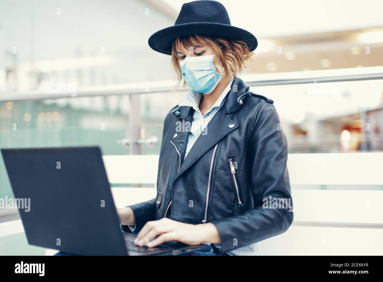 Jeune étudiante universitaire à la mode femme sous masque utilisant un ordinateur portable à l'intérieur Banque D'Images
