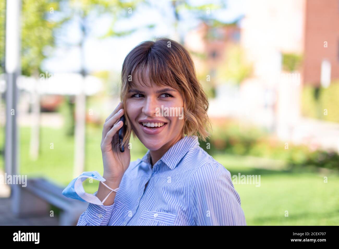 Une jeune femme d'affaires au parc appelle par téléphone en regardant loin Banque D'Images